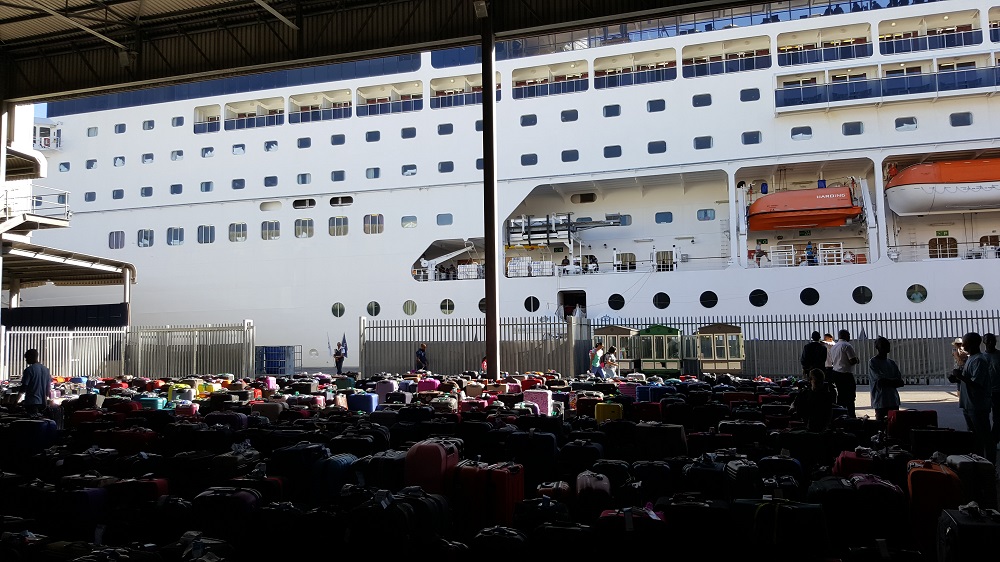 Luggage being sorted at Cape Town Cruise Terminal, with the MSC Sinfonia in the background